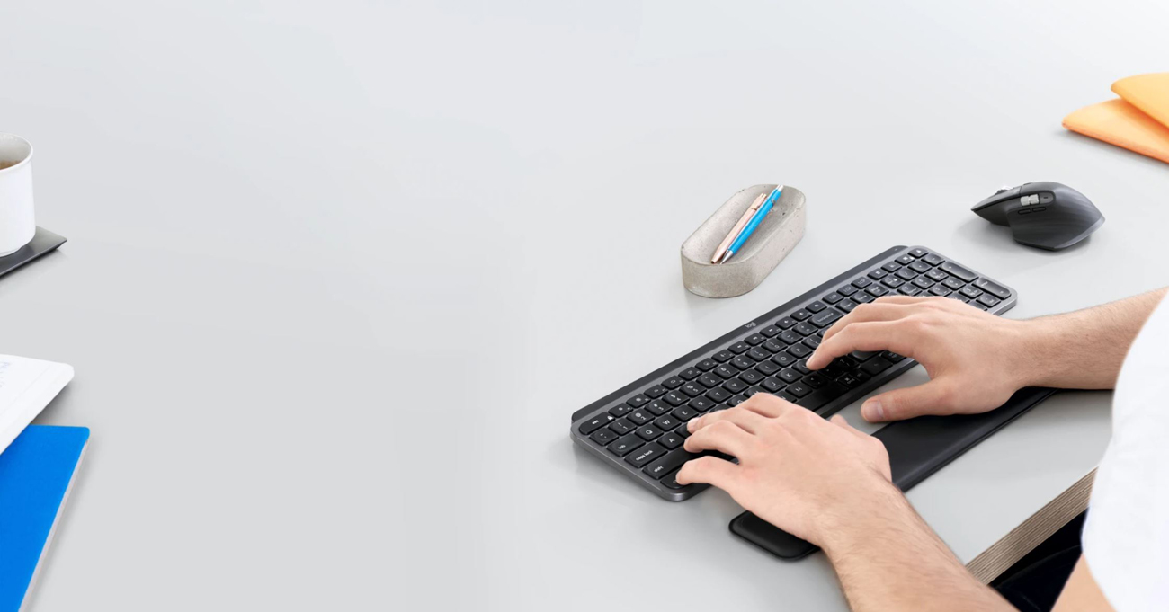 A man is pressing keys on a keyboard and a mouse is next to it.